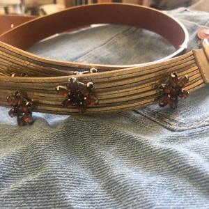 Skärp med detaljer  - Ett guldfärgat skärp med söta små fjärilar på. Några små repor. 50 + frakt (exakta frakten kan vara lägre) 