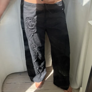 Linnebyxor lågmidjad svarta coolt mönster - Svincoola svarta linnebyxor med unikt mönster. Blomman finns på ett ben bak och ett ben fram.  Supercool detalj på vanliga linnebyxor. Lågmidjade och trendiga, perfekta nu i sommar!✨✨🫶 Jag är 160cm och längden passar bra på mig. 