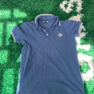 Moncler Pikétröja  - En jättefin Blå Pikétröja från Moncler. Passar för folk som är runt 164. Jag säljer den då den har blivit för liten för mig. Nypris är runt 2,5k men eftersom min är använd så säljer jag den billigt! Kontakta mig för fler bilder eller om ni e intresserade!