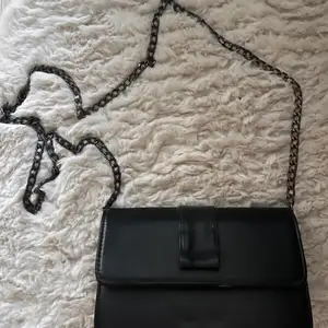 Stilren svart väska med svart kedja, passar till vilken outfit som helst 