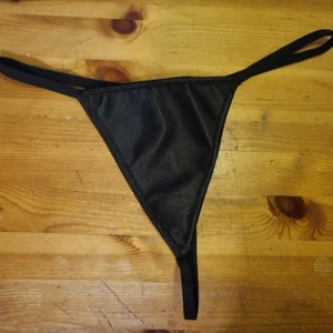 Svart string i satintyg - Ny och oanvänd. Storleken står 3XL, men tror det är mer som en 2XL-XL. Frakten kostar 13kr (1 frimärke) med PostNord.