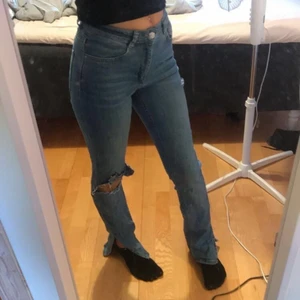 Skit snygga jeans  - Blåa jätte fina lågmidjade jeans med hål på ena knät och slits längst ner på båda benen. Från Gina Tricot i storlek S. 