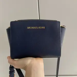 En jättefin mörkblå Michael Kors crossbody väska. Fick den i present för ett bra tag sedan så tyvärr finns ej äkthetsbevis, men kan garantera att den är äkta. 