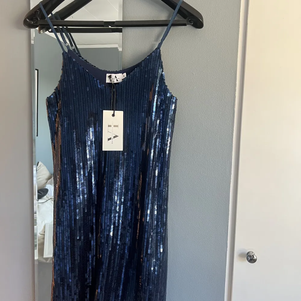 Säljer en blå glittrig klänning från Linn Ahlborg x NA-KD i storlek 32, stor i storleken. Aldrig använd med lapp kvar. Köpt för kanske 2 år sedan. . Klänningar.