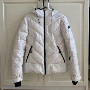 Vit McKinley Slope W Skidjacka - Vind, vattentät, snölås, liftkortsficka. Knappt synlig defekt med små mörka fläckar längst ned vid dragkedjan. Köparen står för frakten. 