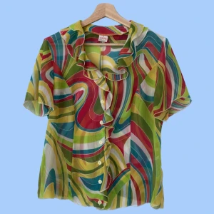 Mönstrad blus - Mönstrad blus med volanger. Färg: flerfärgat mönster Material: 70% polyester, 30% viskos. Ej stretch. Om du har några frågor eller vill se mer bilder är det bara att skicka iväg ett meddelande:)