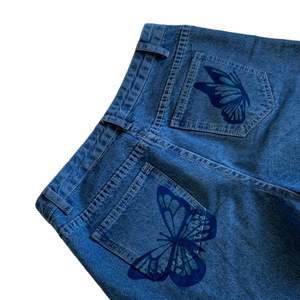Långa vida Blå jeans, med fjärilar målade på fickorna. Har målat trycket själv med tygfärg som håller i tvätten (men tvätta försiktigt).  Jeansen va köpa second hand, men det är i bra skick. Skriv gärna vid frågor. Köparen står för frakt🦋