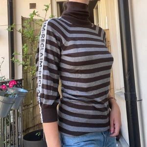 Randig Polotröja - Brun grå randig polotröja med texten ”RECLAIMED-RECLAIMED-RECLAIMED” på ärmarna. Den är gjord av 100% återvunnet material!