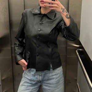 Svart Skinnjacka  - Jättefin svart skinnjacka i storlek L. Känns mer som en S/M. Kort i ärmarna. Nästan aldrig använd. Säljer för 200kr. 