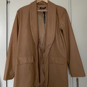 Brun fakeläder kavaj - Säljer min helt oanvända kavaj i fakeläder. Jättesnygg men var tyvärr för stor för mig när jag fick den! 