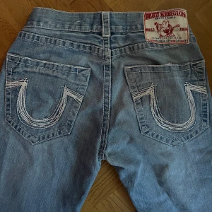True religion jeans - Snygga jeans från true religion! dom är insydda i midjan så dom är inte i storlek 34 som står på bilden, skulle säga att dom passar S-L beroende på hur man vill ha passformen. Mått: midjan ca 39 cm rakt över, innerbenslängd ca 70 cm