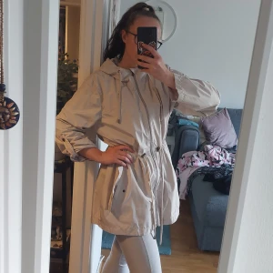 Beige damjacka strl XXL  - Jackan är som ny då den knappt blivit använd. Den är XXL och normal i storlek men går att spänna åt i midjan så kan användas av personer som i vanliga fall har mindre storlekar också.   Materialet är tunt, som en vindjacka typ 😊