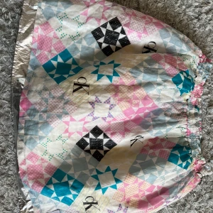 Calvin Klein kjol - Färgglad och väldigt häftig kjol från Calvin Klein! Två lager tyg där det understa är silver och översta är en blandning av färger och CK loggan. Inte använd många gånger, utan i väldigt fint skick! Storleken är 14.