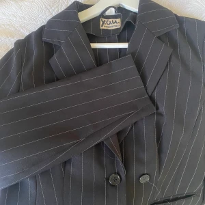 Randig kavaj  - Svart kavaj med vita ränder. Perfekt inför hösten att slänga över vilken outfit som helst! Storleken sitter som en S/M