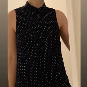 Armlös blus strl 34 - Prickig armlös blus perfekt att ha under kavajen eller en stickad tröja. 