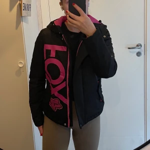 Höst/vinter jacka FOX XS/S som NY! - Säljer en nästintill oanvänd jacka från märket FOX. Svart/rosa i storlek XS. Passar även mig som har S. Perfekt till hösten eller en lättare vinterjacka då den inte är så tjock. Den är fodrad men med en fleece under funkar den säkert under kallare dagar🥰