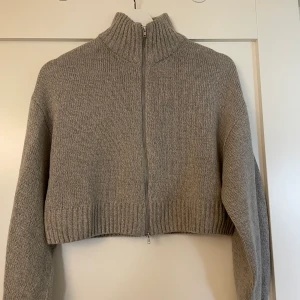 Stickad tröja - Ljusgrå stickad tröja som är lite croppad med en dragkedja. Använd fåtal gånger