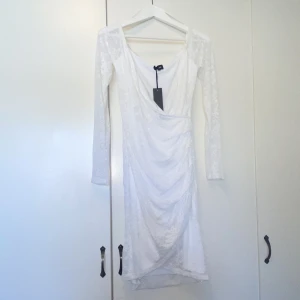 Vit klänning  - Aldrig använd! Wrapklänning/omlottklänning i spets. Endast testad med tagg kvar. 