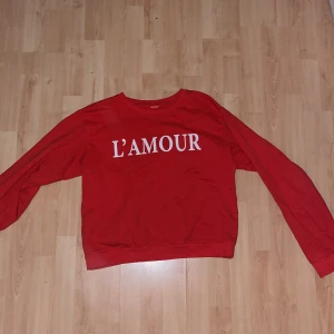 Lindex röda sweatshirt med vit L’amour text  - Lindex röda sweatshirt med vit L’amour text. Tunn sweatshirt i röd färg. Klippt lapp i tröjan. 