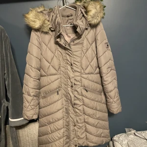 Lång jacka  - Lång jacka med avtagbar päls super varm och praktisk jacka då blixtlåset går att öppna på från båda hållen då jackan är ganska lång obs söndrig ficka och bandet som sitter i mitten av jackan saknas 