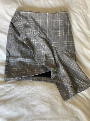 Kjol - Snygg rutig kjol från H&M. I gott skick, beige, svart, vit med volang. Stängs med tunn kedja bak. Stl 34 🤍