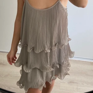 Beige klänning h&m strlk M - Vacker beige plisserad klänning med volanger. Storlek M.