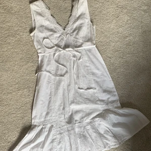 Studentklänning med halvöppenrygg  - Vit klänning som är fin till studenten, med halvöppenrygg, kan ta bättre foto där bak om man skriver privat. Små glittertrådar insytt i tyget:)