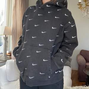 Svart Nike hoodie med Swoosh-detaljer! Köptes i London på ’Size?’. Den är till viss del cropped men lite bredare/oversized. Väldigt mysig! Storleken är XL men jag skulle säga att det är en L eller översized M! Använd rätt så mycket men inga skador någonsin.