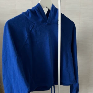 Blå croppad hoodie - Köpt på H&M använd fåtal gånger. Stor och bekväm luva och som ni ser kan man spänna åt midjan om man så vill det :). 