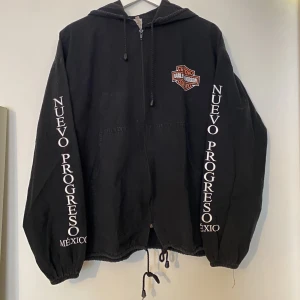 Harley Davidson Mexico jacka  - Harley Davidson Mexico jacka   nuevo progreso  Svart canvas jacka med tryck fram, bak och på ärmarna   En av slut pärlorna på snöret i midjan är halv trasig som man ser på bilderna ( inte så synligt i verkligheten)  Storlek herr M 
