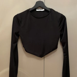 Topp - Långärmad croppad topp i skinande material. Använd någon enstaka gång. Säljer då den blivit för liten för mig. 