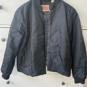 Svart bomberjacka - Svart bomberjacka från Levis i storlek M. Rätt tunn jacka med dragkedjor på fickorna. I bra skick. 