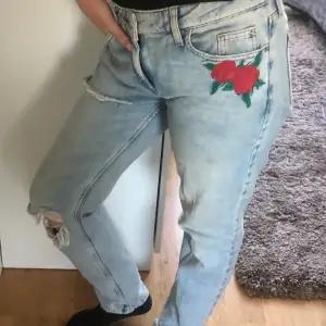 Jeans med dekorativa hål och broderad ros. Storlek: XS (relaxed modell) Märke: Köpt från Cubus. Använd men den är i okej skick. 