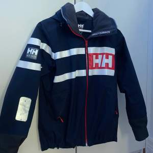 Säljer min mörkblåa Helly Hansen jacka som är vind och vattentät. Har en luva som går att vika in ifall man inte vill att den ska synas. Jackan är i ett bra skick för nästan aldrig använt den.  Köpt jacka för 1499kr. Frakten står köparen för🥰 