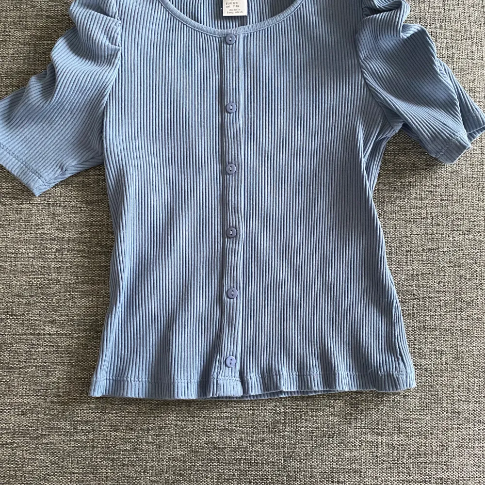 T-shirten är köpt på Lindex och är använd ett fåtal gånger. Den har en fin detalj på ärmarna. (Se bild 3) Den är i storleken 128 och säljs pågrund av att inte blivit använd. T-shirten är i ett mycket bra skick och har en super fin färg!💗😊 Inköpt för 170Kr. T-paidat.