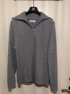 Grå stickad half zip-tröja Whyred - Säljer en grå stickad tröja från Whyred med half zip och bred krage. Tröjan har långärmad passform och ribbade muddar vid ärmslut och nederkant. Perfekt för dig som gillar stilrena och bekväma plagg. Priset kan diskuteras vid snabb affär!
