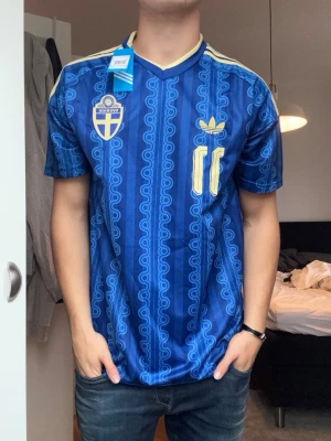 Sverige fotbollströja Elanga - Säljer en fotbollströja Vm 2026 Sverige bortatröja med tryck baktill där de står ”Elanga” och har nummer 11.  Perfekt för dig som vill stötta Sverige på match eller träning. Köptes på en marknad utomlands!!