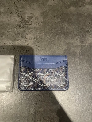 Blå kortfodral  - Snyggt blått kortfodral från  med klassiskt mönster i vitt och brunt. Fodralet har flera kortfack och är gjort i en kombination av läder och canvas. Perfekt för dig som vill ha en stilren och exklusiv accessoar i fickan.