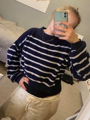 Randig stickad tröja  - Snygg mörkblå stickad tröja med vita ränder. Tröjan har en avslappnad passform, rund halsringning och långa ärmar. Perfekt för lager på lager och enkel att styla till olika outfits. Egensydd slit som syns på bild 3. 