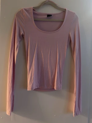 Ljusrosa långärmad topp Gina Tricot - SOFT TOTCH GINA TRÖJA Säljer en ljusrosa långärmad topp från Gina Tricot i mjuk bomull. Toppen har en rund, djup urringning och en slim passform som sitter snyggt på kroppen. Perfekt att matcha med jeans eller kjol för en enkel och clean look.