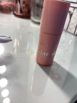 Glazed highlighter stick  - Glazed highlighter stick i färgen pink champagne från Makeup Mekka. Kommer i en smidig rosa tub som är enkel att ta med i väskan. Ger ett snyggt glow med en ljus, skimrande finish. Perfekt för att framhäva kindben och andra ansiktsdrag. Använd fåtal gånger