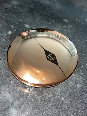 Charlotte Tilbury puderfoundation - Snygg puderfoundation från Charlotte Tilbury i en rund, lyxig roséguldig dosa med spegelblank finish och logga på locket. Perfekt att ha i väskan för touch-ups under dagen. Ger en jämn och naturlig bas.