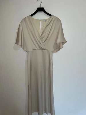 Beige satin klänning från bubbelroom - Beige/cremefärgad klänning från BUBBLEROOM Occasion, storlek 34.  Endast använd vid ett tillfälle. Pris kan ändras vid snabb affär.   