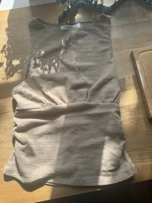 Beige ärmlös linnetopp - Säljer en beige ärmlös linnetopp med diskret strukturmönster. Super fin, men säljer pgr av att jag inte änvönder den🩷. Perfekt för varma dagar eller som layering-piece.