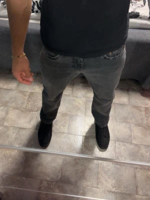  Levi’s jeans - Säljer ett par grå tvättade jeans med rak passform och klassisk femficksdesign. Jeansen har en avslappnad look och är tillverkade i denim. Perfekta för dig som gillar en enkel men snygg stil.