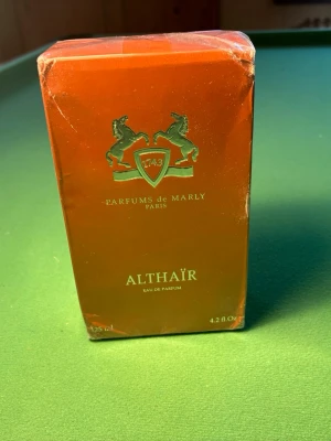 Parfums de Marly Althaïr EdP 125ml - Althaïr Eau de Parfum helt oanvänd från Parfums de Marly i en snygg orange flaska med silverfärgat lock. Flaskan har ett upphöjt emblem med två hästar och texten '1743'. Förpackningen matchar flaskans färg och har gulddetaljer.