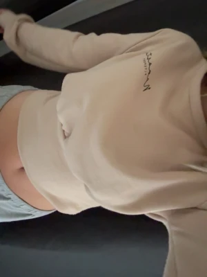 Beige cropped hoodie från prettylittlething - Sitter som Xs-S!!!  Snygg beige cropped hoodie från Sisters Point med broderad text på bröstet. 