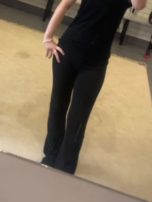 Svarta utsvängda leggings - Säljer ett par svarta leggings med utsvängda ben. De är höga i midjan och har en tight passform upptill som går över i en vidare siluett nedtill. Perfekta att styla med en enkel topp eller hoodie. Materialet ser stretchigt och bekvämt ut.