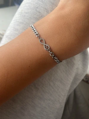 Silverfärgat armband med evighetssymbol - Snyggt armband i silverfärg med en tunn kedja och en evighetssymbol i mitten. Armbandet har en enkel och stilren design som passar till många olika stilar. Tillverkat i metall med blank finish och smidig låsning.