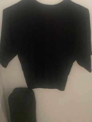 Svart croppad t-shirt - En enkel svart croppad t-shirt med korta ärmar och rund halsringning. Perfekt för en avslappnad och stilren look. Passar till det mesta och är lätt att matcha med andra plagg.